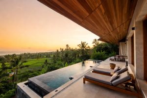 Luxury 2-bedroom villa in the Bali rental market with private infinity pool overlooking rice fields and ocean at golden hour sunset.